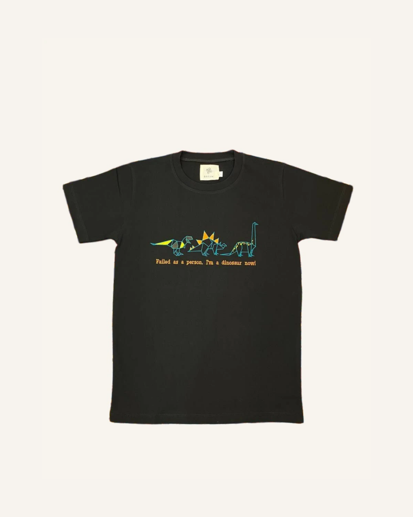 تی‌شرت مشکی دایناسور — تصویر واقعی محصول با زمینه شیری